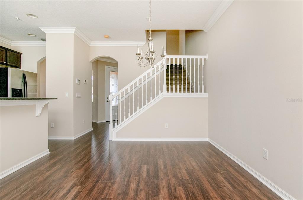 A dining area with dark wood floors, a white staircase, and a hanging chandelier — 9426 SILVER BUTTONWOOD STREET, ORLANDO, FL