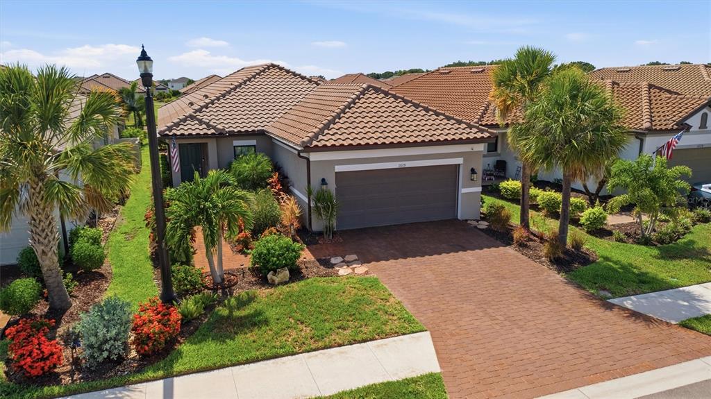 A single-story house with a tiled roof, brick driveway, and palm trees in the front yard — 11115 DEVONBRIDGE DRIVE, PALMETTO, FL