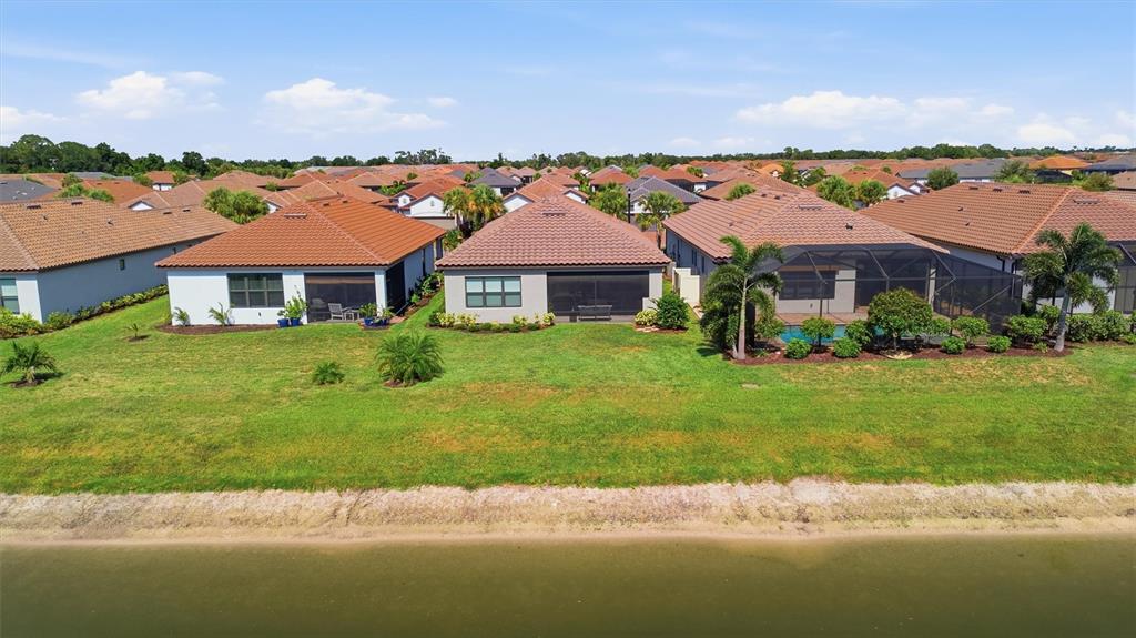 An aerial view shows several suburban houses with tiled roofs situated along a waterfront — 11115 DEVONBRIDGE DRIVE, PALMETTO, FL