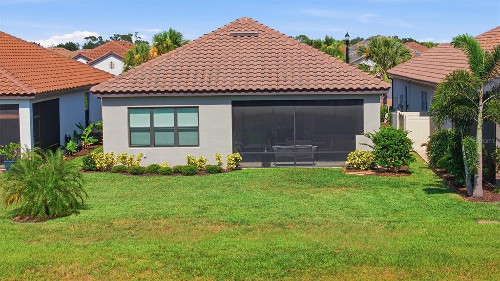 The rear exterior of a single-story house features a tiled roof, stucco walls, and a lanai — 11115 DEVONBRIDGE DRIVE, PALMETTO, FL