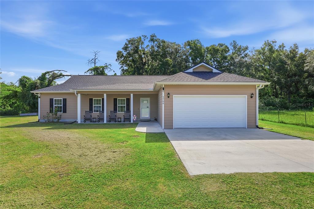 A single-story house with tan siding, a white garage door, and a covered front porch — 5766 SW COUNTY ROAD 18, FORT WHITE, FL
