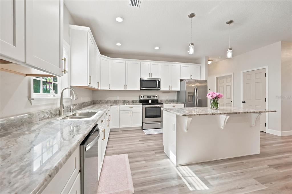 A kitchen with white cabinets, stainless steel appliances, and gray marble-patterned countertops — 5766 SW COUNTY ROAD 18, FORT WHITE, FL
