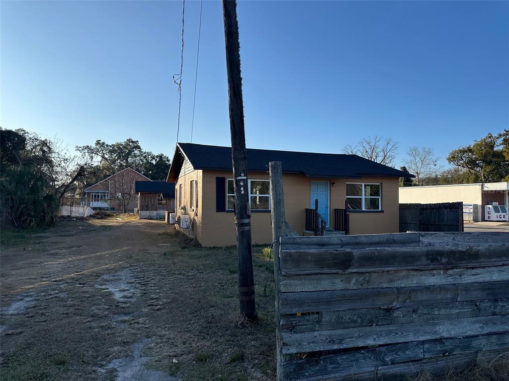 A tan single-story house with a blue door sits behind a wooden fence — 9710 NE 21ST AVENUE, ANTHONY, FL