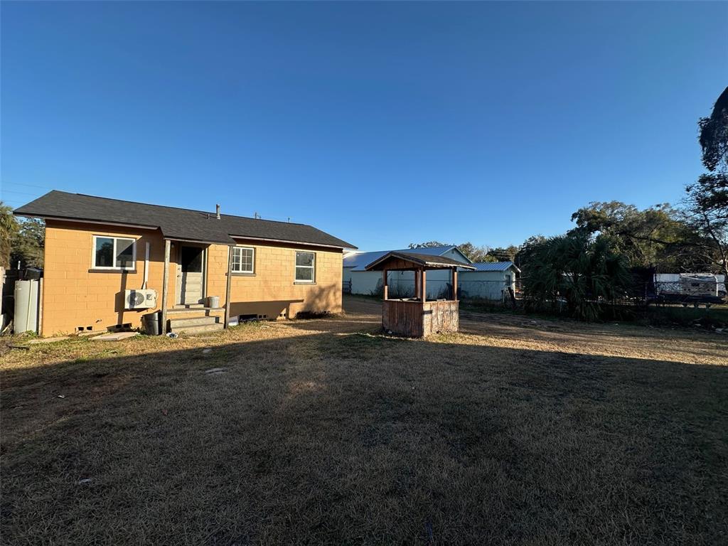 The exterior of a tan block house features a small wooden well in the yard — 9710 NE 21ST AVENUE, ANTHONY, FL
