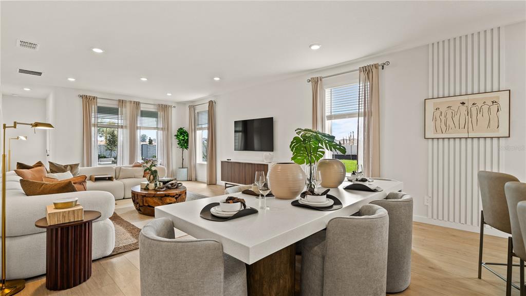 A bright open-concept living and dining area features modern furniture, neutral tones, and large windows — 3116 ROCKWOOD WAY, MINNEOLA, FL