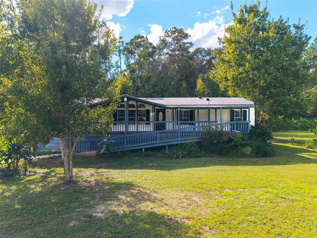 A white mobile home with a dark porch and ramp sits next to a storage shed — 17822 COMMONWEALTH AVENUE N, POLK CITY, FL