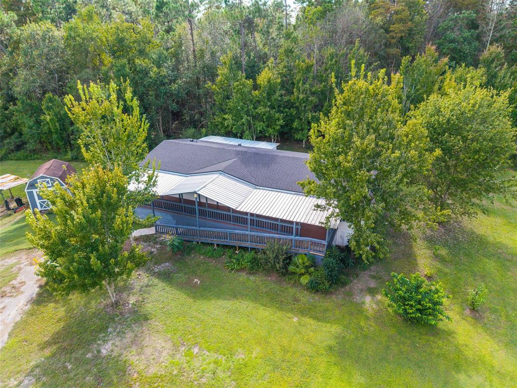 An aerial view shows a house with a metal roof, a shed, and a carport — 17822 COMMONWEALTH AVENUE N, POLK CITY, FL