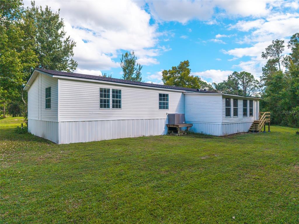 An aerial view shows a house with a wrap-around porch, a shed, and a carport — 17822 COMMONWEALTH AVENUE N, POLK CITY, FL