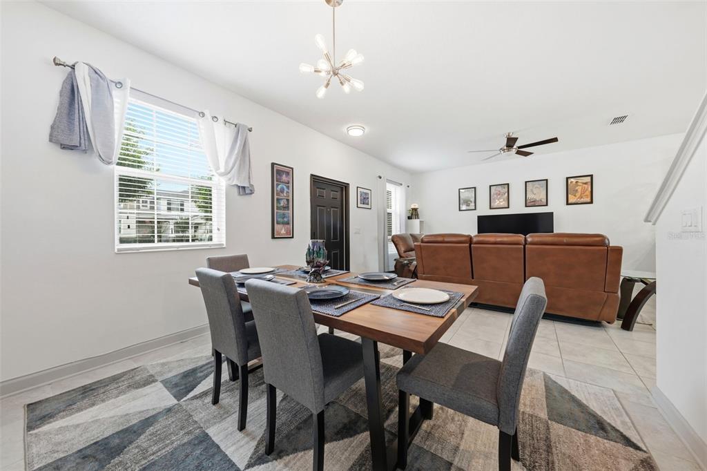A dining area with a wooden table and grey chairs sits before a living room — 11025 SUSPENSE DRIVE, WINTER GARDEN, FL