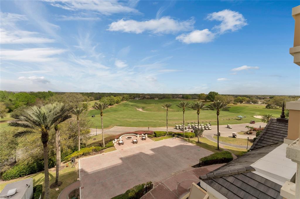 An elevated view of a paved patio overlooking a golf course with palm trees — 7593 GATHERING DRIVE UNIT 309, REUNION, FL