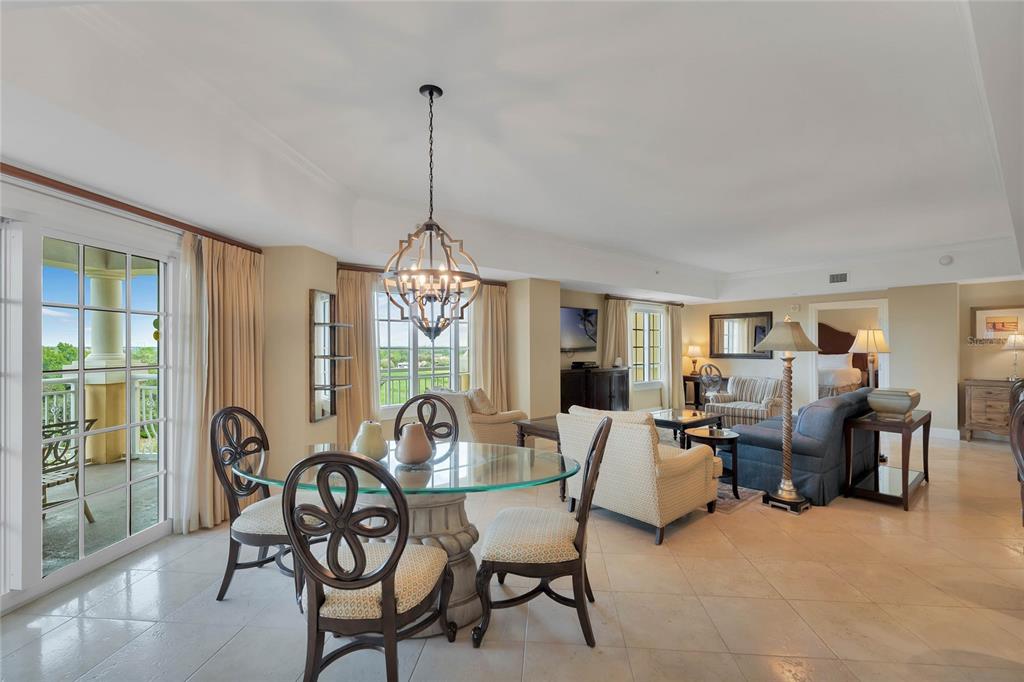 A dining area with a glass table and chandelier opens into a living room with balcony — 7593 GATHERING DRIVE UNIT 309, REUNION, FL