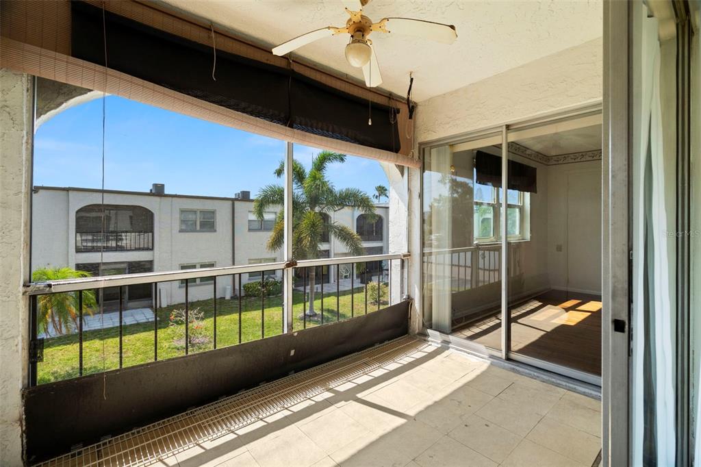 A screened-in balcony with tile flooring, a ceiling fan, and views of a neighboring building — 7701 STARKEY ROAD UNIT 504, SEMINOLE, FL