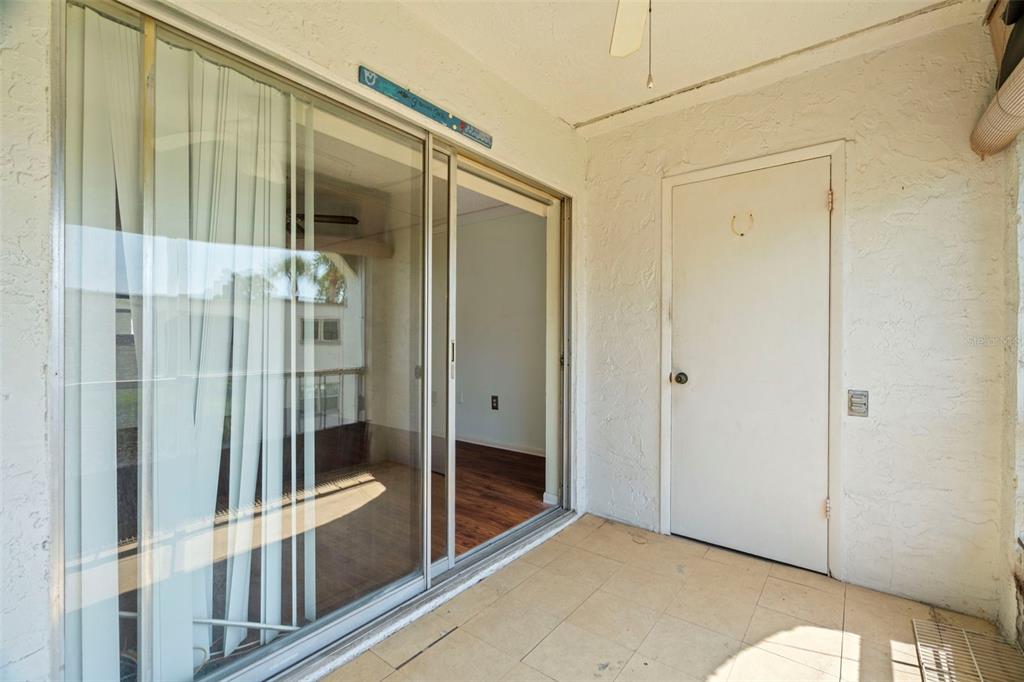 A covered balcony features tiled flooring, a sliding glass door, and a white entry door — 7701 STARKEY ROAD UNIT 504, SEMINOLE, FL