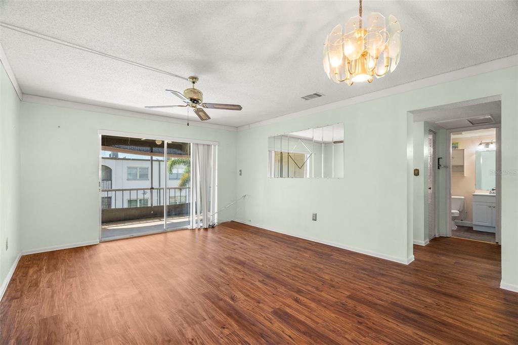 A living room with wood-look flooring, a ceiling fan, a chandelier, and a sliding glass door — 7701 STARKEY ROAD UNIT 504, SEMINOLE, FL