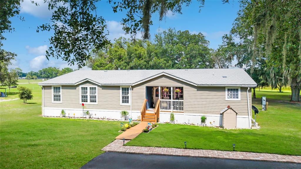 A single-story manufactured home with tan siding, a gray roof, and a front porch — 12651 SE COUNTY ROAD 337, DUNNELLON, FL