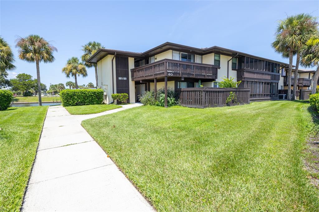 A two-story apartment building with a wooden balcony and a sidewalk leading to the entrance — 60 CLUB HOUSE DRIVE UNIT 208, PALM COAST, FL