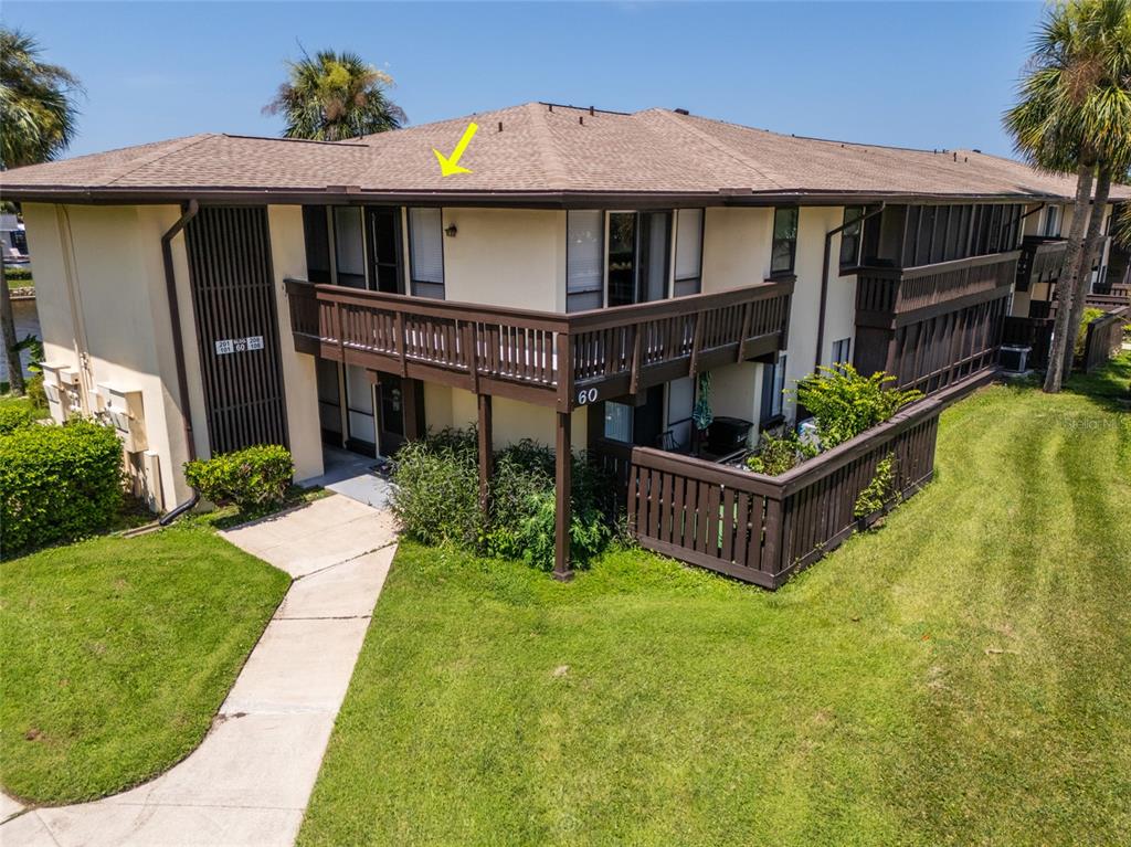 An exterior view of a two-story apartment building with a wooden balcony and brown roof — 60 CLUB HOUSE DRIVE UNIT 208, PALM COAST, FL
