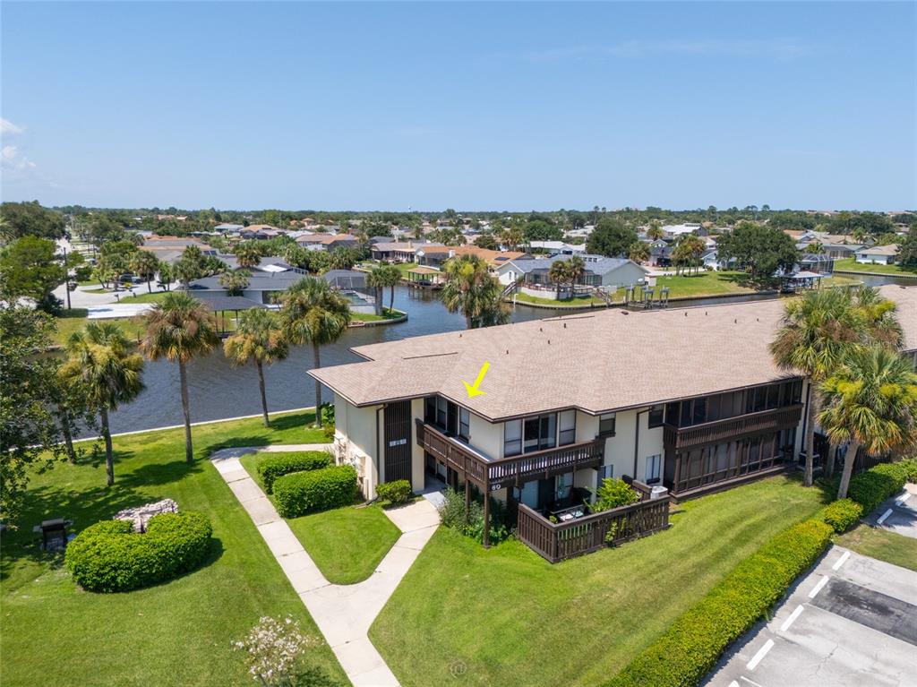 An aerial view shows a two-story apartment building with a balcony overlooking a canal — 60 CLUB HOUSE DRIVE UNIT 208, PALM COAST, FL