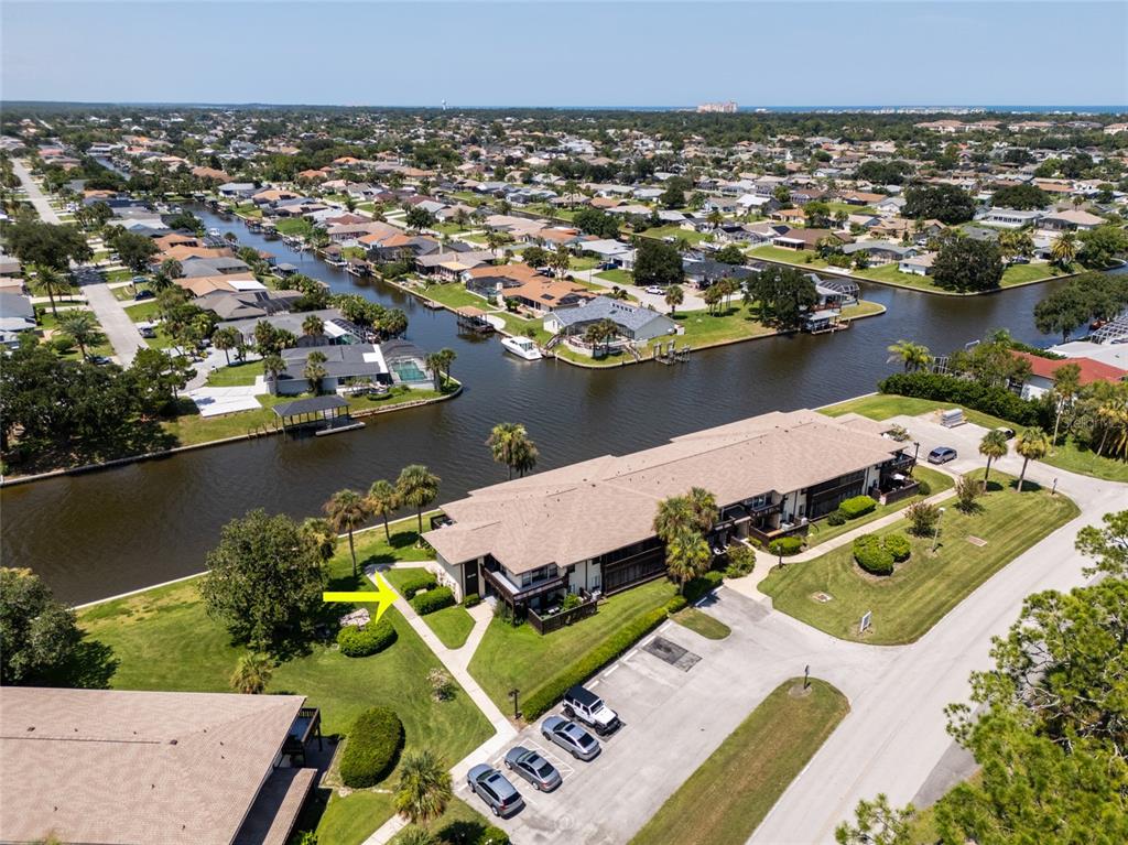 An aerial view shows a multi-unit residential building situated along a canal with parking — 60 CLUB HOUSE DRIVE UNIT 208, PALM COAST, FL