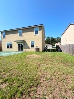 The back exterior of a two-story tan house features a sliding glass door and windows — 45170 DUTTON WAY, CALLAHAN, FL