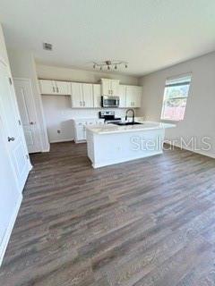 A kitchen features white cabinets, a central island with a sink, and wood-look flooring — 45170 DUTTON WAY, CALLAHAN, FL