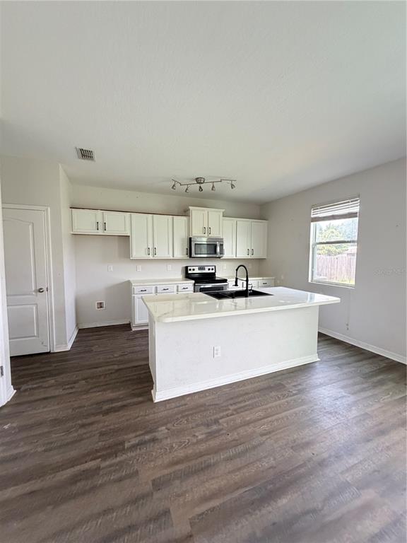 A kitchen features white cabinets, a central island with a sink, and dark wood-look flooring — 45170 DUTTON WAY, CALLAHAN, FL