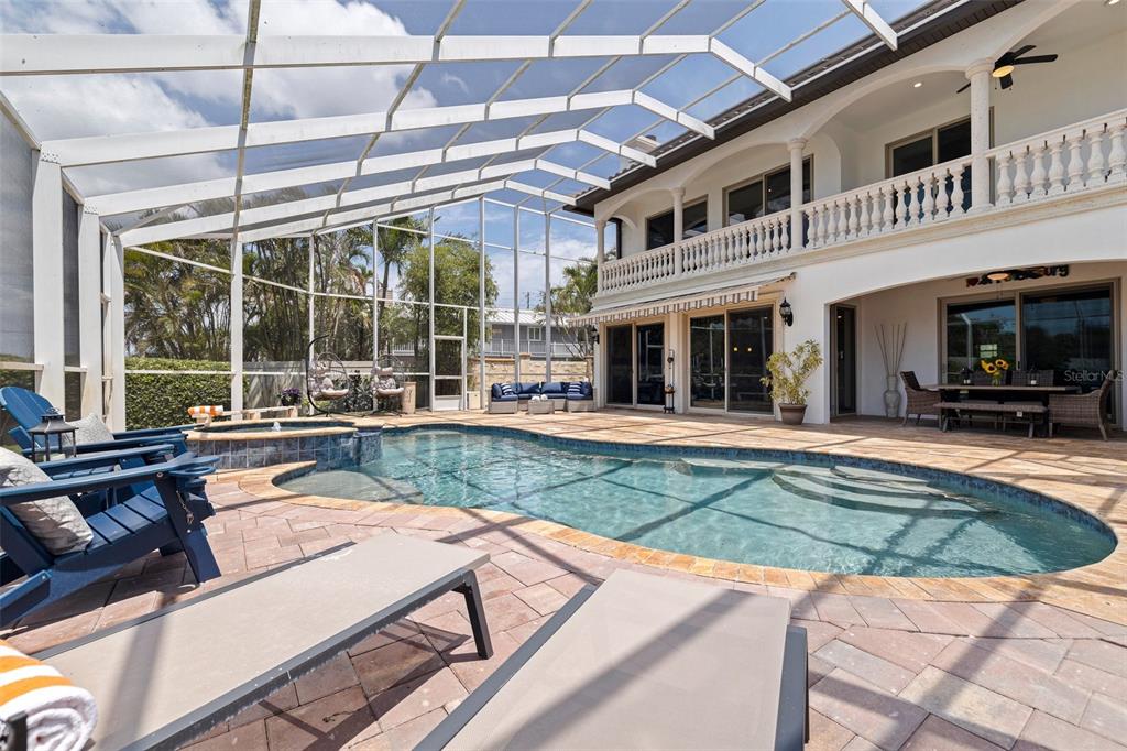 A screened-in patio features a swimming pool, hot tub, and outdoor seating area — 3931 POMPANO DRIVE SE, ST PETERSBURG, FL