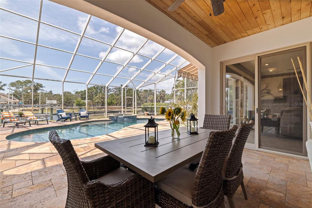 A covered patio features a dining set, a swimming pool, and a screened-in enclosure — 3931 POMPANO DRIVE SE, ST PETERSBURG, FL