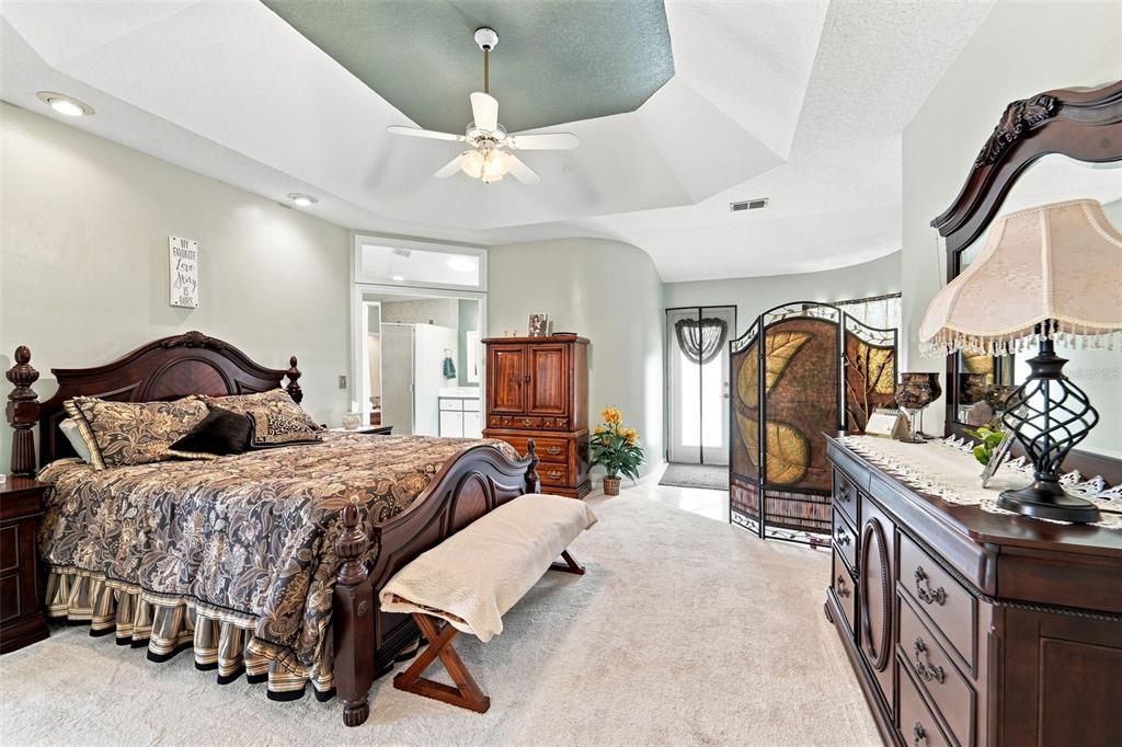 A bedroom features a wooden bed frame, a dresser with a mirror, and a ceiling fan — 102 BIRKWOOD COURT, DEBARY, FL