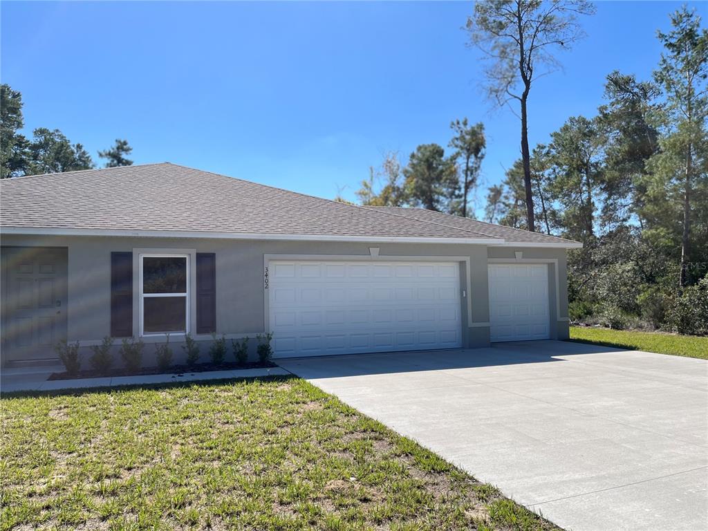A single-story house exterior features a two-car garage, a single-car garage, and a front window — 3402 SW 165TH LOOP, OCALA, FL