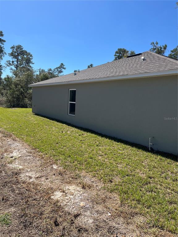 A side view of a gray house exterior with a single window and grass yard — 3402 SW 165TH LOOP, OCALA, FL