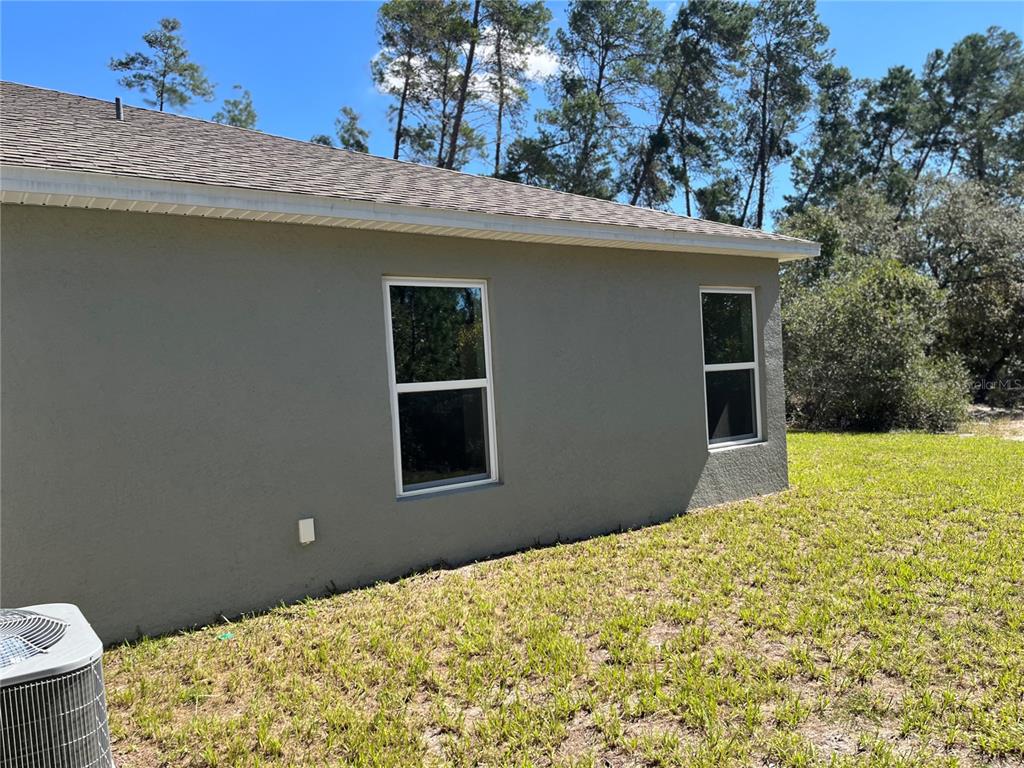 The exterior side wall of a house features two windows and an air conditioning unit — 3402 SW 165TH LOOP, OCALA, FL