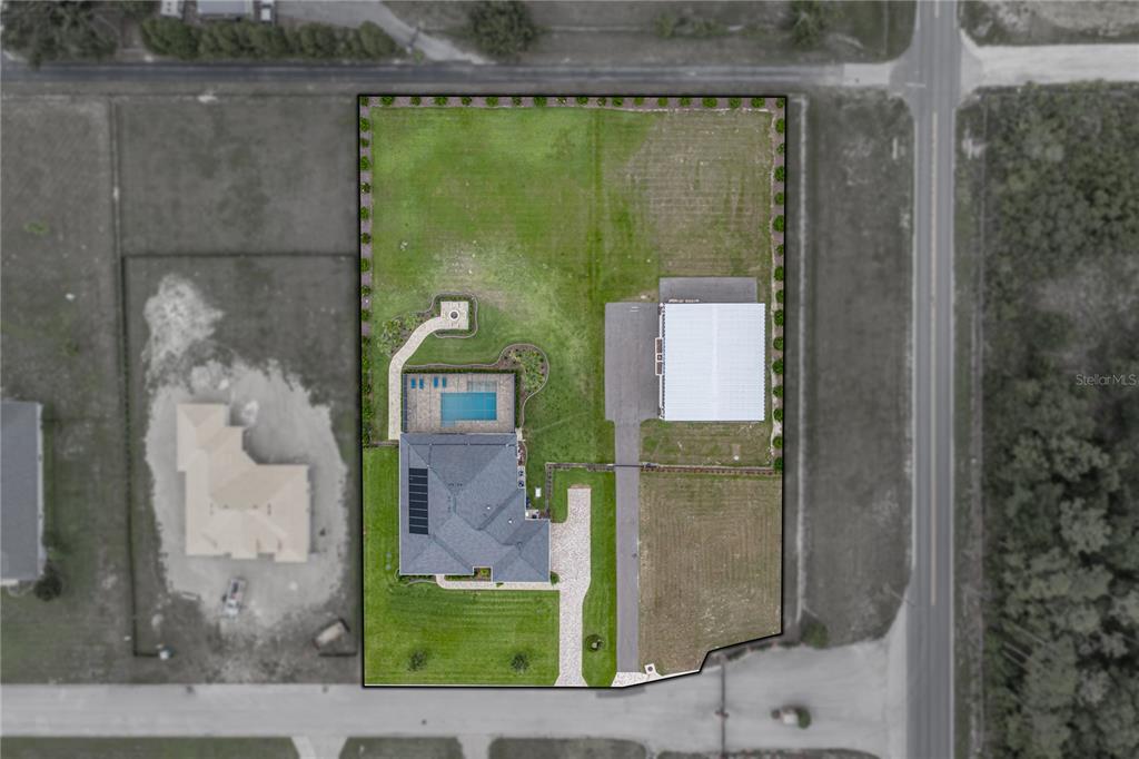 This aerial view shows a house with a pool, a detached garage, and a large yard — 32655 WESLEY WAY, DADE CITY, FL