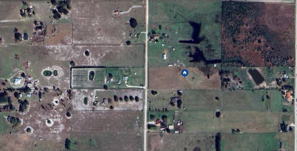An aerial view shows a vacant rectangular plot of land surrounded by rural residential properties — 52 MEADOW WAY, FROSTPROOF, FL