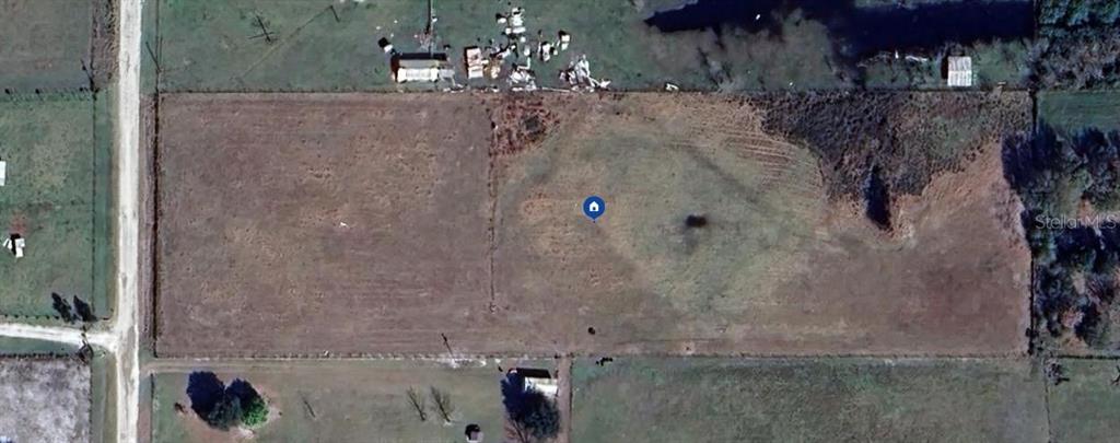 This aerial view shows a rectangular, undeveloped plot of land bordered by a dirt road — 52 MEADOW WAY, FROSTPROOF, FL