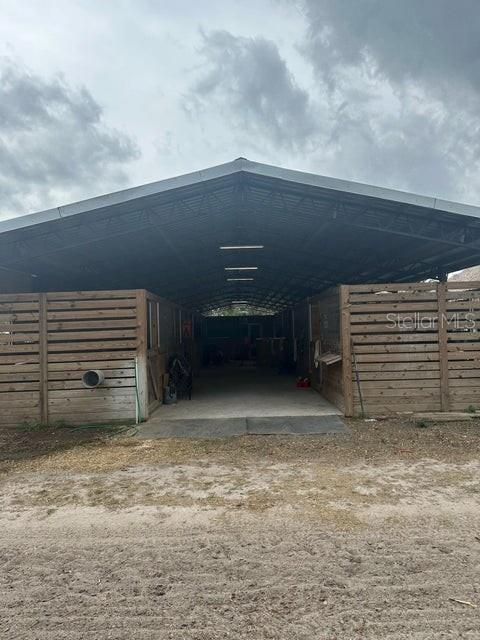 A metal-roofed barn features wooden stall walls and a central concrete aisle — 3525 D RD, LOXAHATCHEE GROVES, FL