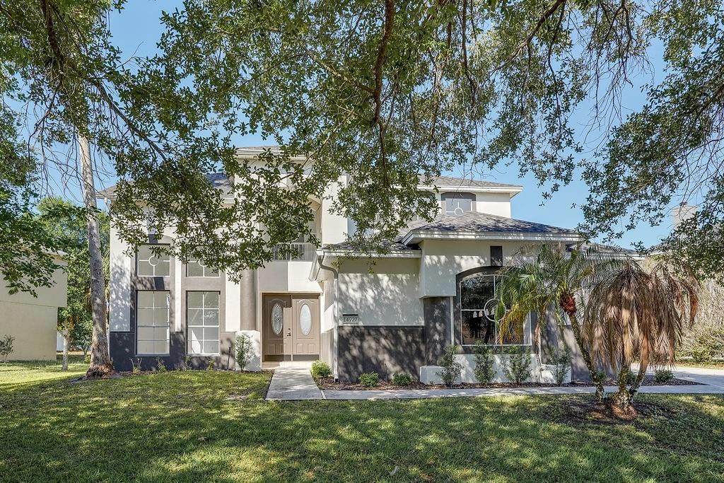 A two-story house with a light-colored stucco exterior, dark trim, and a front walkway — 14927 FAVERSHAM CIRCLE, ORLANDO, FL