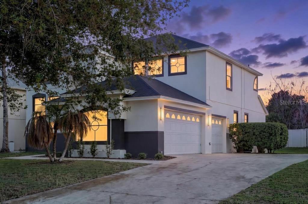 A two-story house with a white and gray exterior, a three-car garage, and a concrete driveway — 14927 FAVERSHAM CIRCLE, ORLANDO, FL