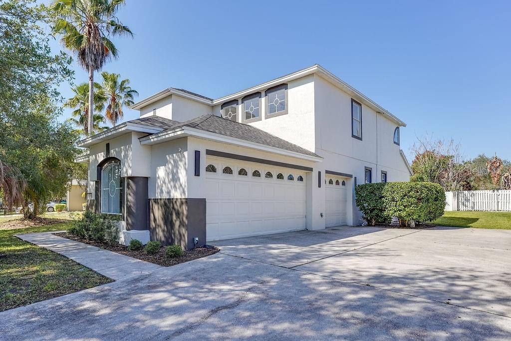 A two-story house with a white stucco exterior, a three-car garage, and a concrete driveway — 14927 FAVERSHAM CIRCLE, ORLANDO, FL