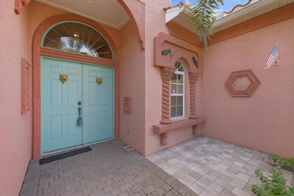 The exterior entrance features a light blue double door, arched transom window, and stone pavers — 210 RIO TERRA, VENICE, FL