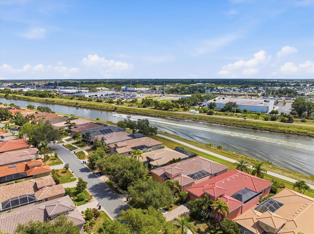 An aerial view shows a suburban neighborhood with houses bordering a wide canal — 210 RIO TERRA, VENICE, FL
