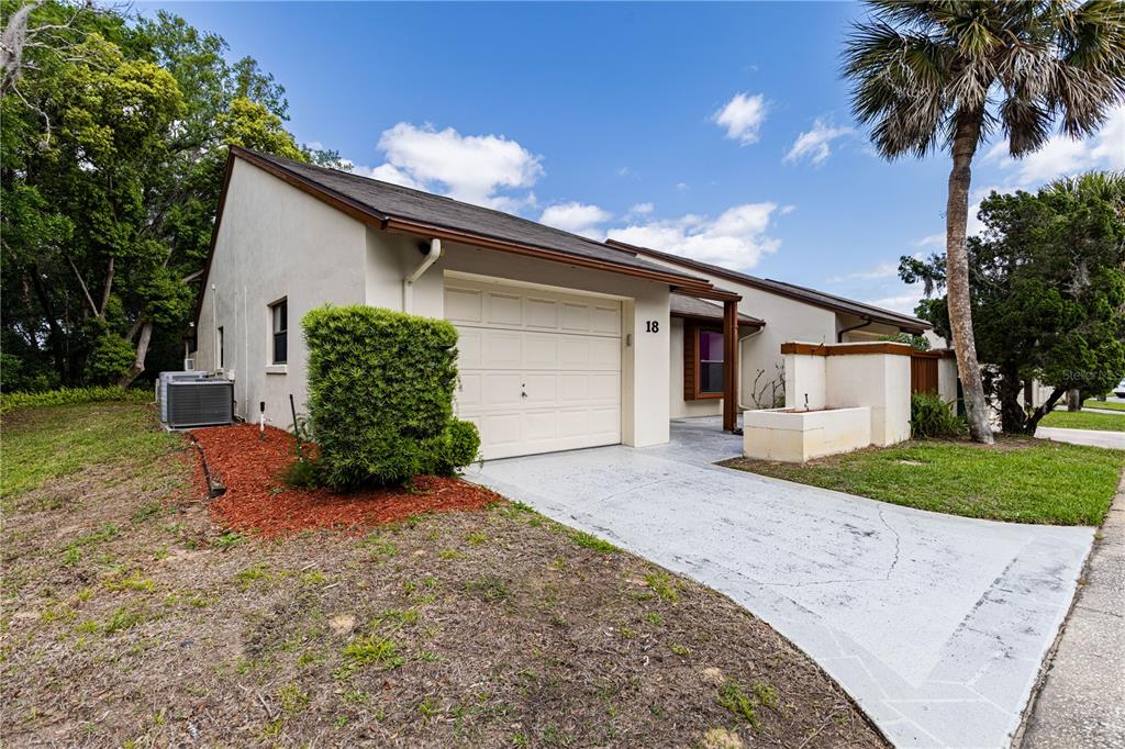 A single-story house with a white stucco exterior, a one-car garage, and a concrete driveway — 2681 WASHINGTON AVENUE UNIT 18, EUSTIS, FL