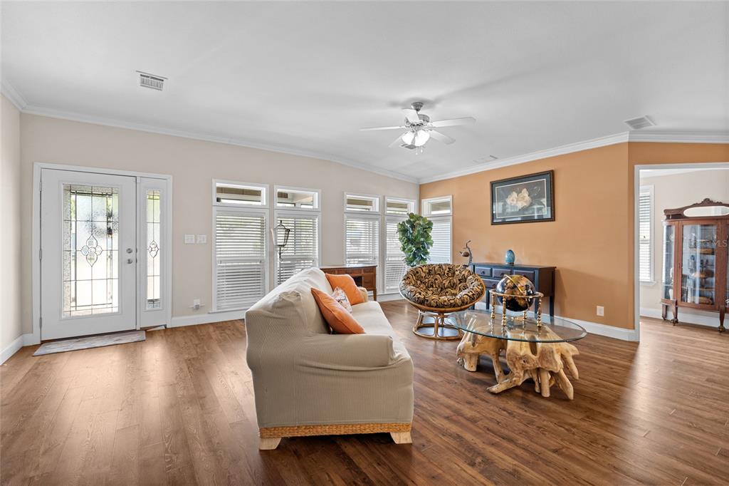 A living room features wood-look flooring, a beige sofa, a glass-topped coffee table, and windows — 2715 9TH AVENUE N, ST PETERSBURG, FL