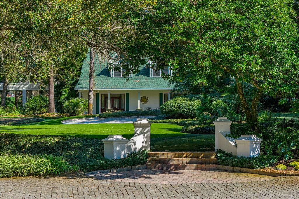 A two-story house with a green roof sits behind a brick driveway and stone pillars — 3515 GALLAGHER ROAD, DOVER, FL