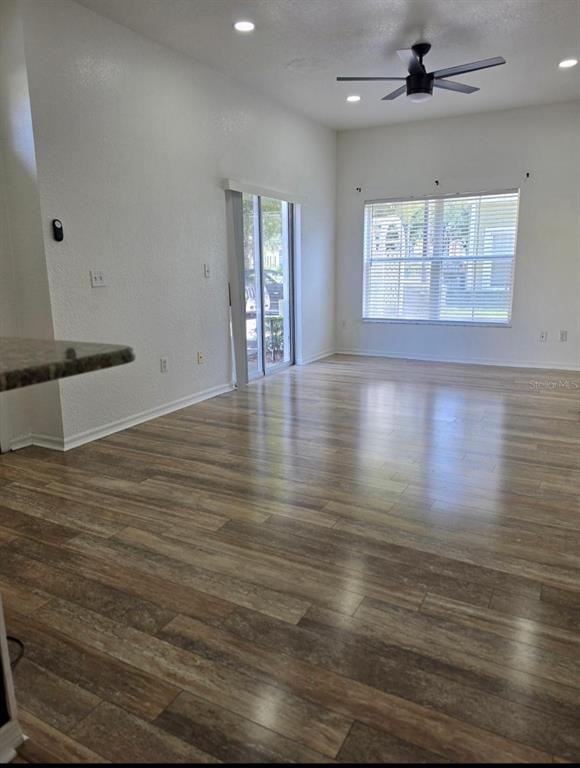 An empty room features wood-look flooring, a ceiling fan, recessed lighting, and a sliding glass door — 2260 SAN VITAL DRIVES UNIT 108, KISSIMMEE, FL
