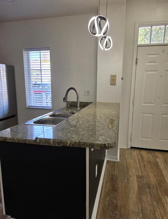 A kitchen features a granite countertop, a double sink, and modern pendant lighting — 2260 SAN VITAL DRIVES UNIT 108, KISSIMMEE, FL