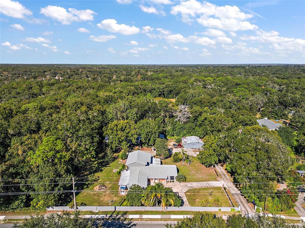 An aerial view shows a house and detached garage surrounded by dense trees and vegetation — 1661 VOTAW ROAD, APOPKA, FL