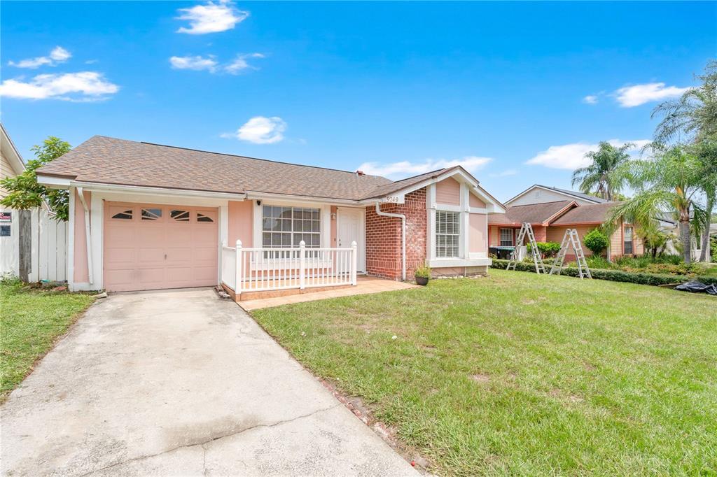 A single-story house with a pink exterior, brick accents, a garage, and a front porch — 9249 SPRING VALE ROAD, ORLANDO, FL