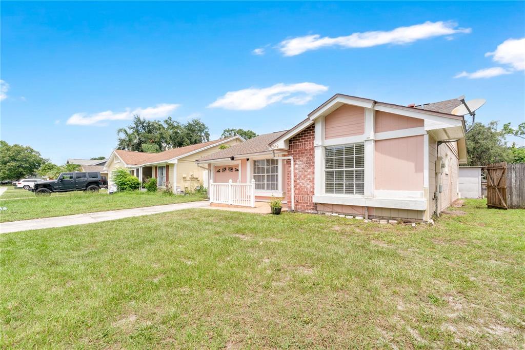A single-story house with pink siding, a brick facade, and a white front porch railing — 9249 SPRING VALE ROAD, ORLANDO, FL