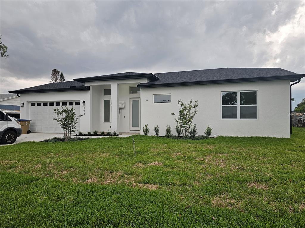 A single-story white house with a black roof, garage, and front entryway — 292 GARDENIA ROAD, KISSIMMEE, FL